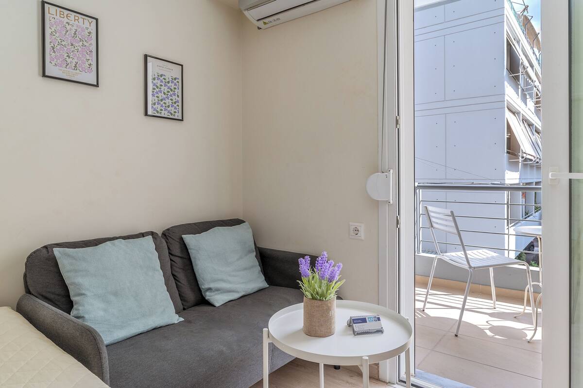 A small living area with a sofa, a small table with a plant, and two framed pictures on the wall.