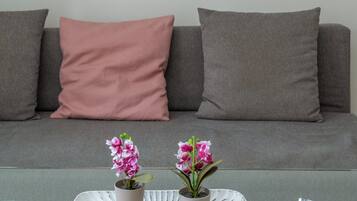 Una sala de estar con un sofá, una mesa de centro con dos plantas en macetas, y un cuadro con la Torre Eiffel.