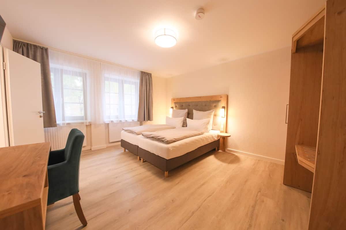 A bedroom with a bed, bedside table, chair, and wardrobe.