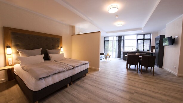 A modern hotel room with a large bed, a desk, and a TV. - 24 7 Selfcheckin Pferdemarkt (Leer)