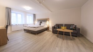 A modern bedroom with a bed, a sofa, a small table, and a desk. - 24 7 Selfcheckin Pferdemarkt (Leer)