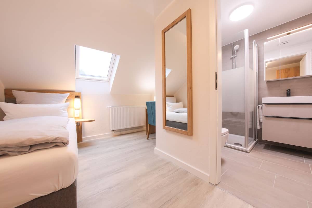 A bedroom with a bed, bedside table, and a window.