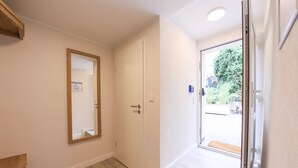 A hallway with a wooden floor, a white door, and a glass door leading outside. - 24 7 Selfcheckin Pferdemarkt (Leer)