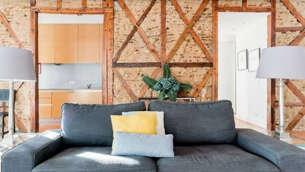 A modern living room with a grey sofa, two lamps, and a wooden wall with a geometric pattern. - Eighteen 21 Houses - Casa de São Paulo (Lisboa)