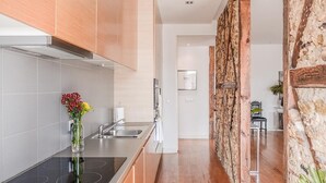A modern kitchen with a built-in stove, stainless steel sink, and wooden cabinets. - Eighteen 21 Houses - Casa de São Paulo (Lisboa)