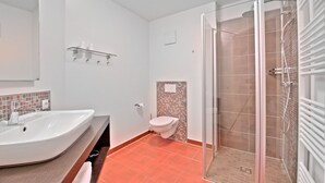 Een badkamer met een douche, wastafel en toilet.