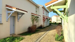 A narrow street with houses, a gravel path, and a green metal structure. - Little Happiness house residence with pool & spa (Talmont-Saint-Hilaire)