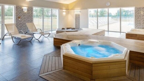 A spacious indoor area with a hot tub, wooden flooring, and large windows. - Little Happiness house residence with pool & spa (Talmont-Saint-Hilaire)