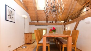 Un coin repas avec une table et des chaises en bois, un lustre et un tableau encadré au mur.