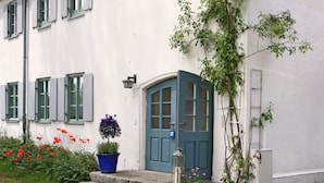Un bâtiment blanc avec une porte bleue, une plante en pot et une lanterne sur les marches.