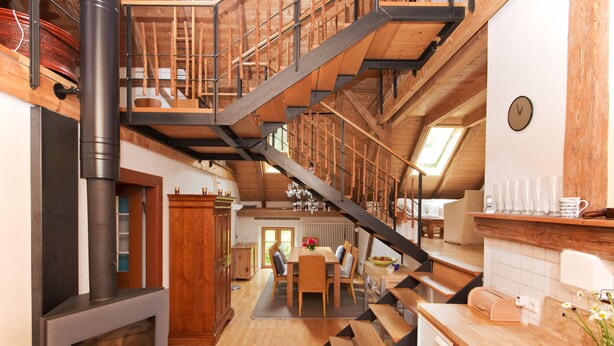 Une cuisine spacieuse avec un escalier en bois, un coin repas et une vue sur l’extérieur.