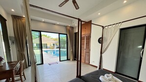 A hotel room with a bed, a desk, and a view of a swimming pool. - Spacious Private Pool Villa (Tambon Rawai)