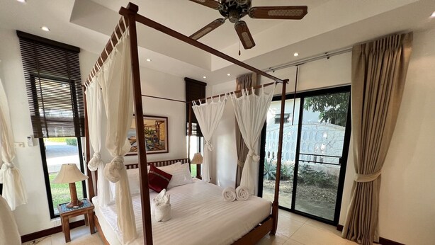 A four-poster canopy bed with a view of the outdoors through large windows. - Spacious Private Pool Villa (Tambon Rawai)