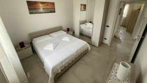 Ein Schlafzimmer mit einem Bett, einem Nachttisch, einem Schminktisch, einem Spiegel und einem Bild an der Wand.