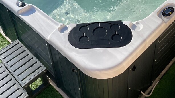 Ein Whirlpool mit Bedienfeld, umgeben von einer Holzterrasse und Topfpflanzen.