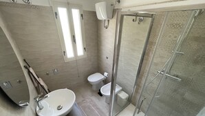 Ein Badezimmer mit einer Duschkabine, einem Waschbecken und zwei Toiletten.