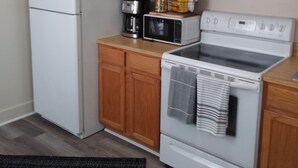 Uma cozinha com armários de madeira, geladeira branca, micro-ondas, cafeteira e fogão.