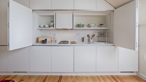 Une cuisine moderne avec des meubles blancs, un plan de travail en bois et divers appareils de cuisine.