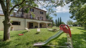 Una casa con balcón, tobogán y columpio en el jardín.
