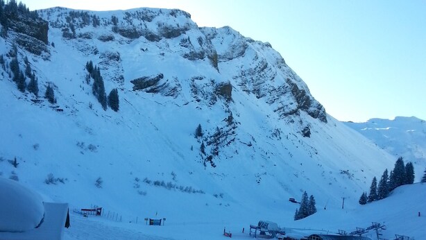 Eine verschneite Berglandschaft mit einer Seilbahn und einem Gebäude im Vordergrund.