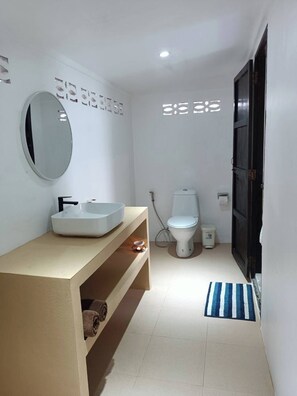 A modern bathroom with a white sink, mirror, and toilet.