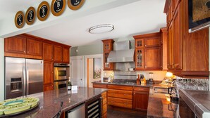 A modern kitchen with wooden cabinets, stainless steel appliances, and a granite countertop.