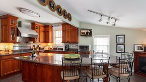 A spacious kitchen with wooden cabinets, a large island with bar stools, and a dining area with a fireplace.