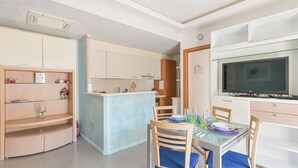 A modern kitchen with a central island, a dining area with two chairs, and a television mounted on the wall. - Norb House Lerici ( CIN IT011016C2Y3WHZASD) (Lerici)