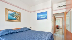 A bedroom with a bed, two framed paintings, a chair, and a wardrobe. - Norb House Lerici ( CIN IT011016C2Y3WHZASD) (Lerici)