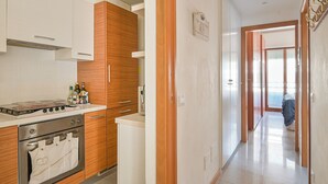 A kitchen with wooden cabinets, a stove, and a refrigerator. - Norb House Lerici ( CIN IT011016C2Y3WHZASD) (Lerici)