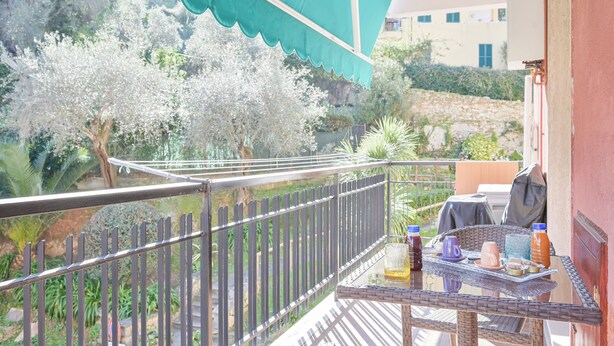 A balcony with a table, chairs, and a green umbrella. - Norb House Lerici ( CIN IT011016C2Y3WHZASD) (Lerici)