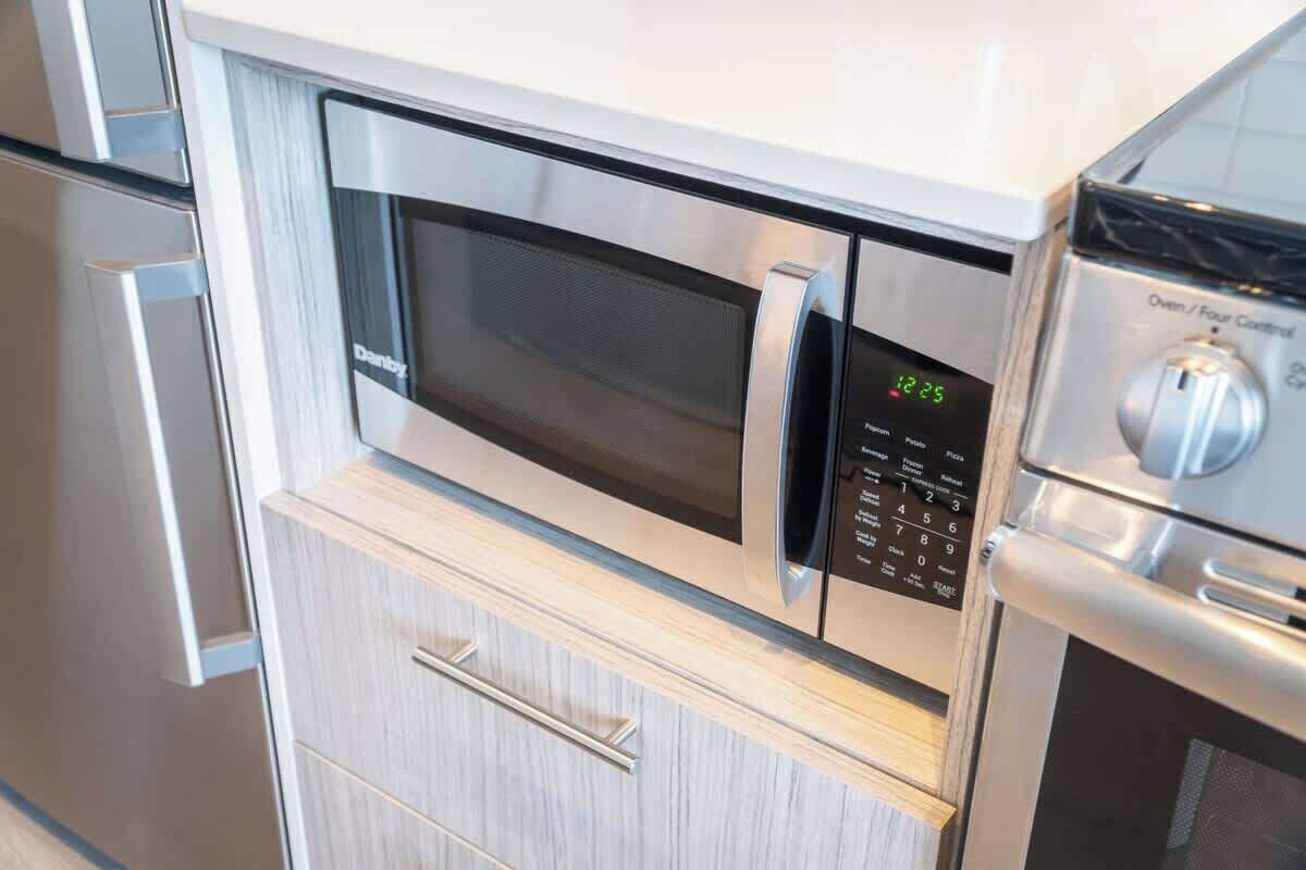 Eine moderne Küche mit eingebauter Mikrowelle und Backofen, ausgestattet mit einer Digitaluhr und Bedienblende.