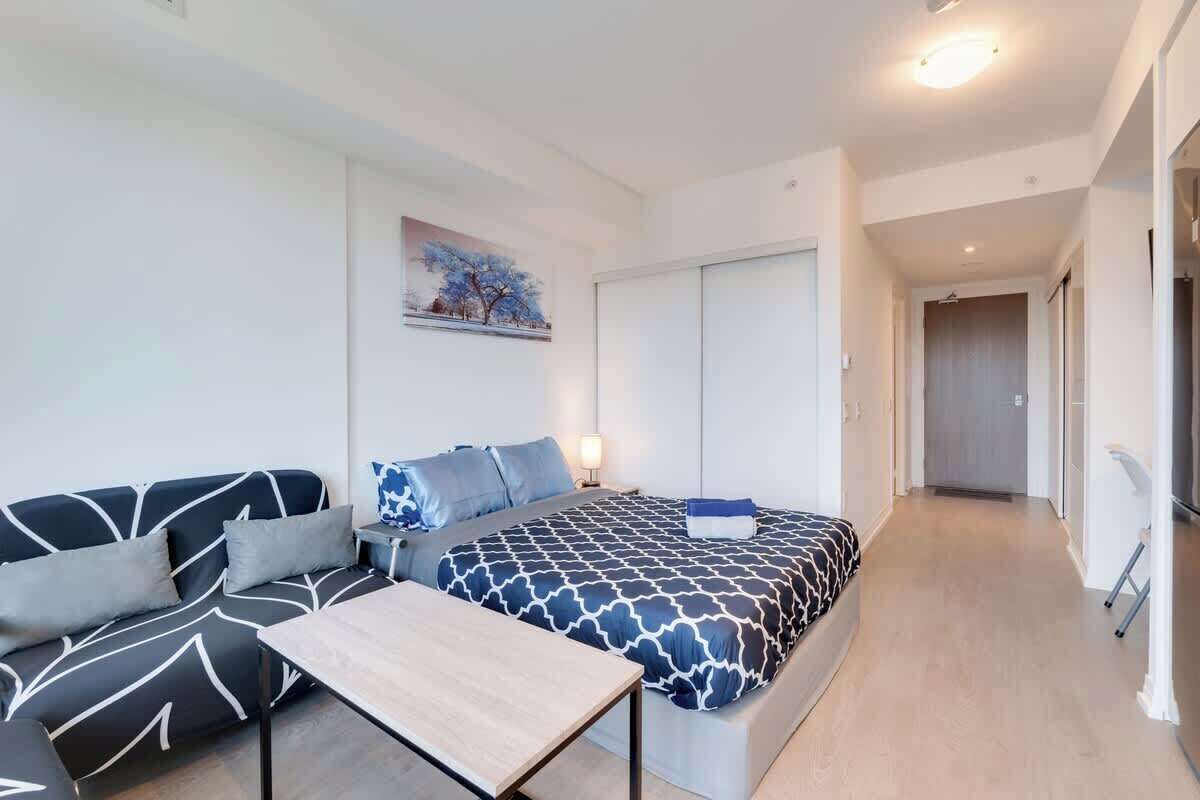 Een moderne hotelkamer met een bank, een bed met beddengoed met een patroon, een nachtkastje en een schilderij aan de muur.