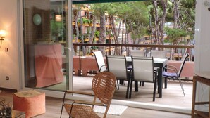 Un balcon avec une table et des chaises pour prendre les repas, un fauteuil à bascule en osier et une porte vitrée donnant sur l’extérieur.