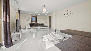 Un saló modern amb un sofà modular, una taula de centre i una televisió sobre un moble blanc.