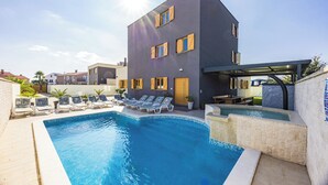 Edifici modern amb piscina, gandules i zona coberta.