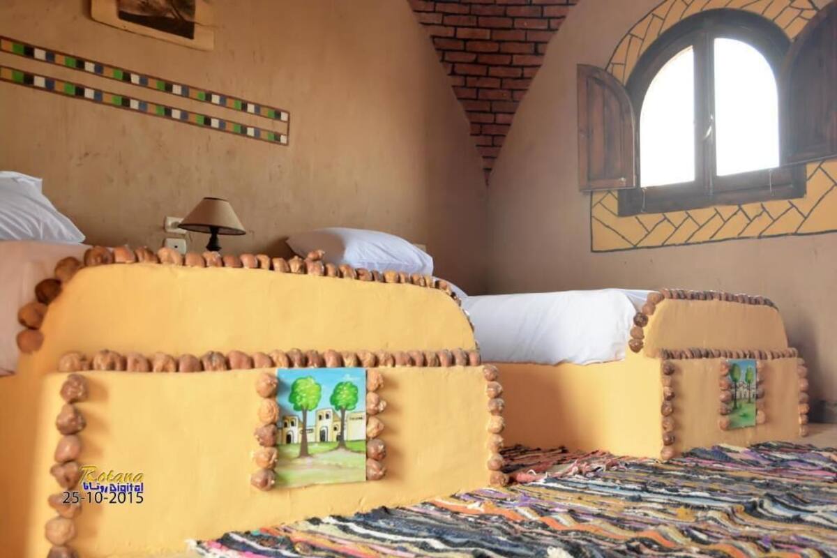 Une chambre avec deux lits, chacun doté d’une tête de lit au design original et agrémentée d’un petit tableau.