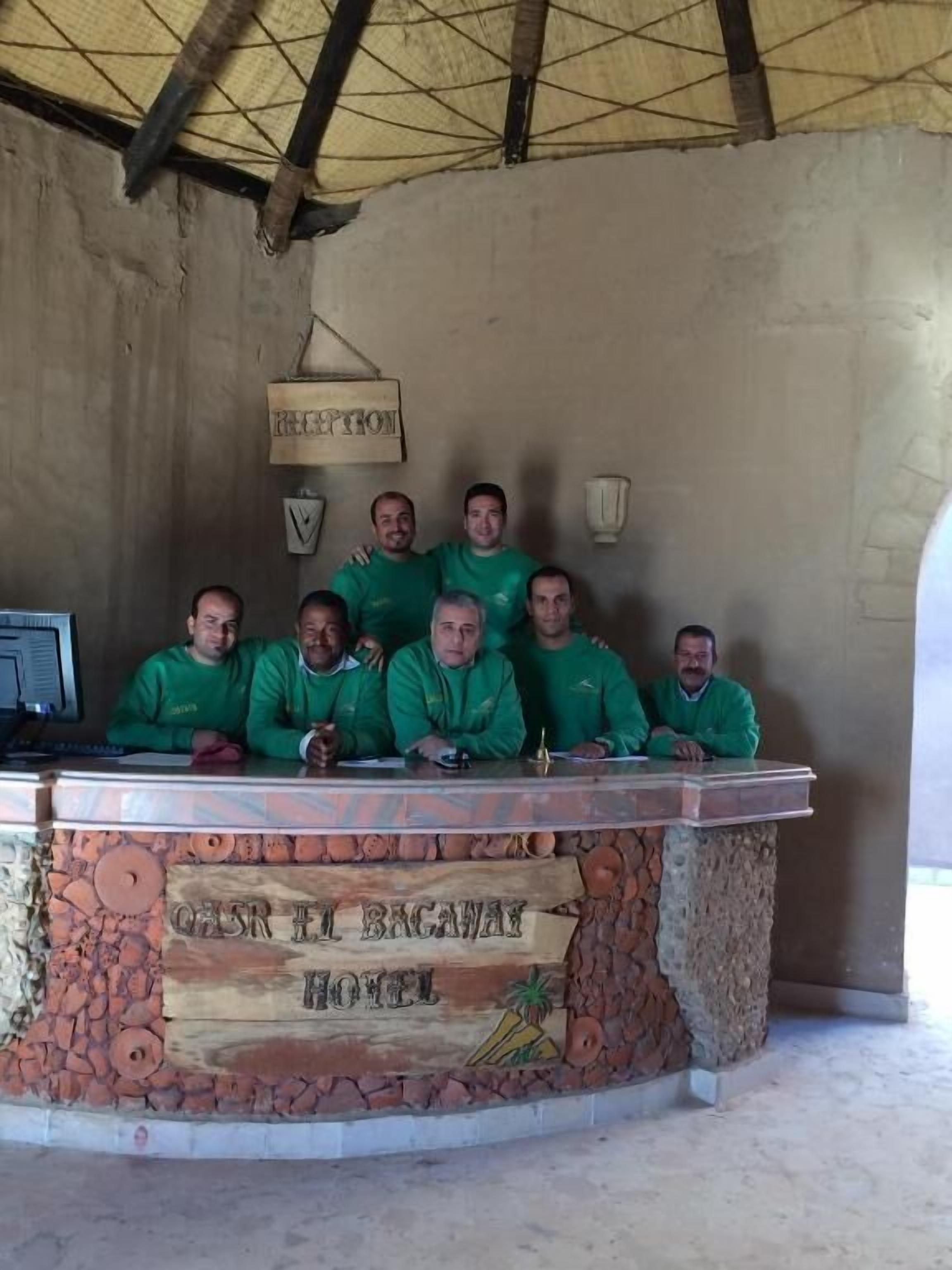 Un groupe de personnes est assis à un comptoir devant une enseigne indiquant « OASR IT BAGAWAN HOTEL ».