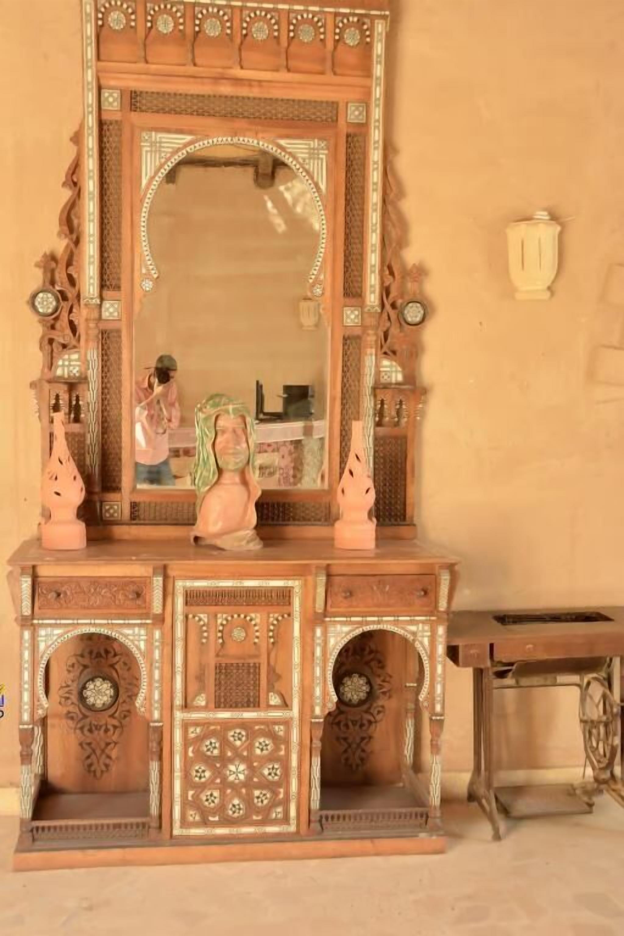 A wooden cabinet with intricate carvings and a large mirror.