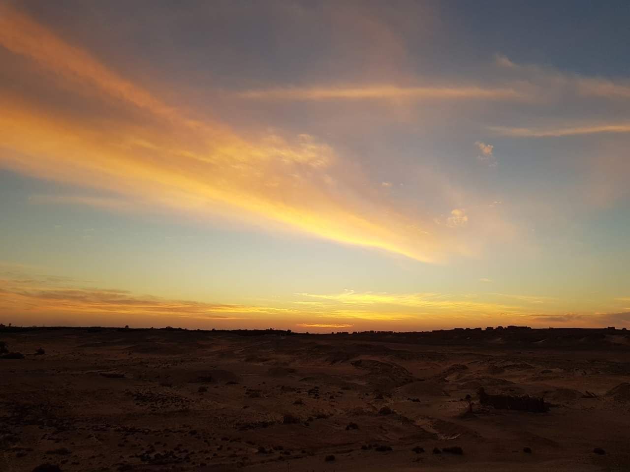 Un paysage désertique au coucher du soleil, sous un ciel dégagé.