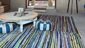 Una habitación con una cama, una mesa redonda y un colorido tapete a rayas.