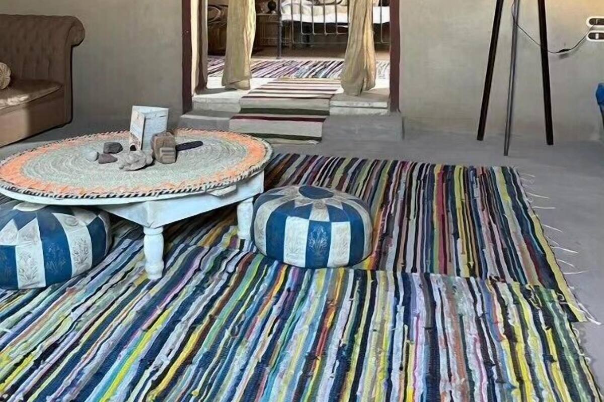 Une pièce avec un lit, une table ronde et un tapis rayé aux couleurs vives.