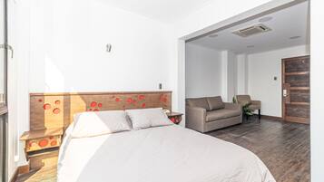 Een hotelkamer met een groot bed, een slaapbank en een houten hoofdbord met rode accenten.