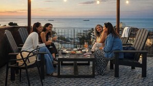Un grupo de personas sentadas en una mesa con vistas al océano y barcos a lo lejos.