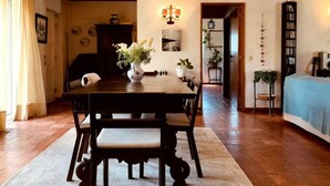Un coin repas avec une table et des chaises en bois, un lustre et une bibliothèque en arrière-plan.