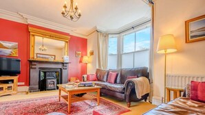 Een woonkamer met een open haard, een bank, een salontafel en een televisie.