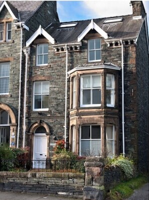 A stone building with a corner bay window, a white door, and a stone staircase leading to the entrance. - The Gables Sleeps 14 (7 Bedrooms) - Central Keswick Location (Keswick)