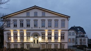 En stor, historisk bygning med en symmetrisk facade, mange vinduer og en central indgang med trapper op til den.