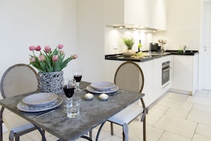 A dining table set with plates, glasses, and a vase of flowers. - Berliner Hof, App 5, Westerland, Sylt (65sqm) (Sylt)