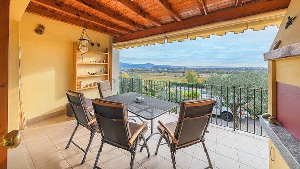 Un balcon doté d’un plafond en bois, une table avec des chaises et une vue sur la campagne.